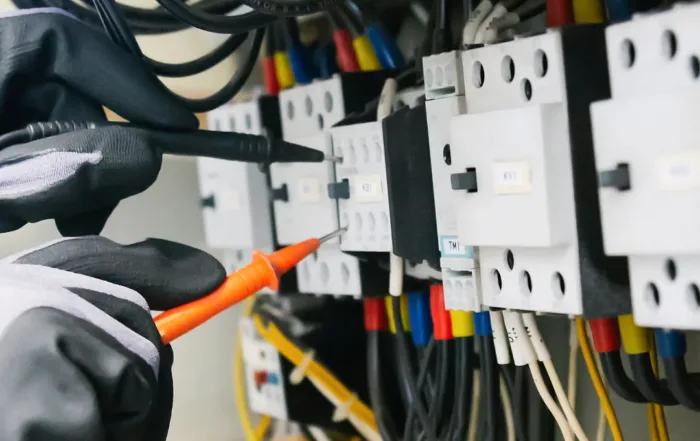 Electrician testing and repairing wiring inside an electrical panel