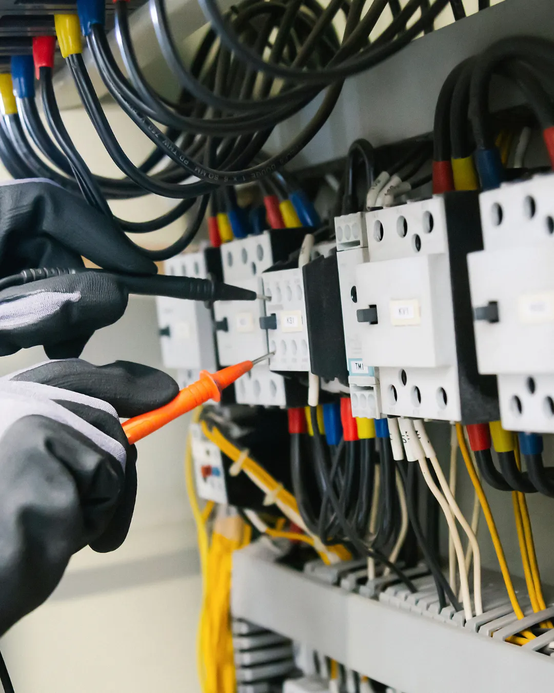 Electrician testing and repairing wiring inside an electrical panel