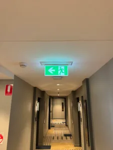 Illuminated emergency exit sign in a hotel hallway installed by Xceed Electrical.