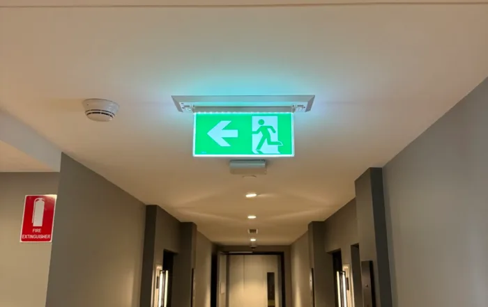 Illuminated emergency exit sign in a hotel hallway installed by Xceed Electrical.