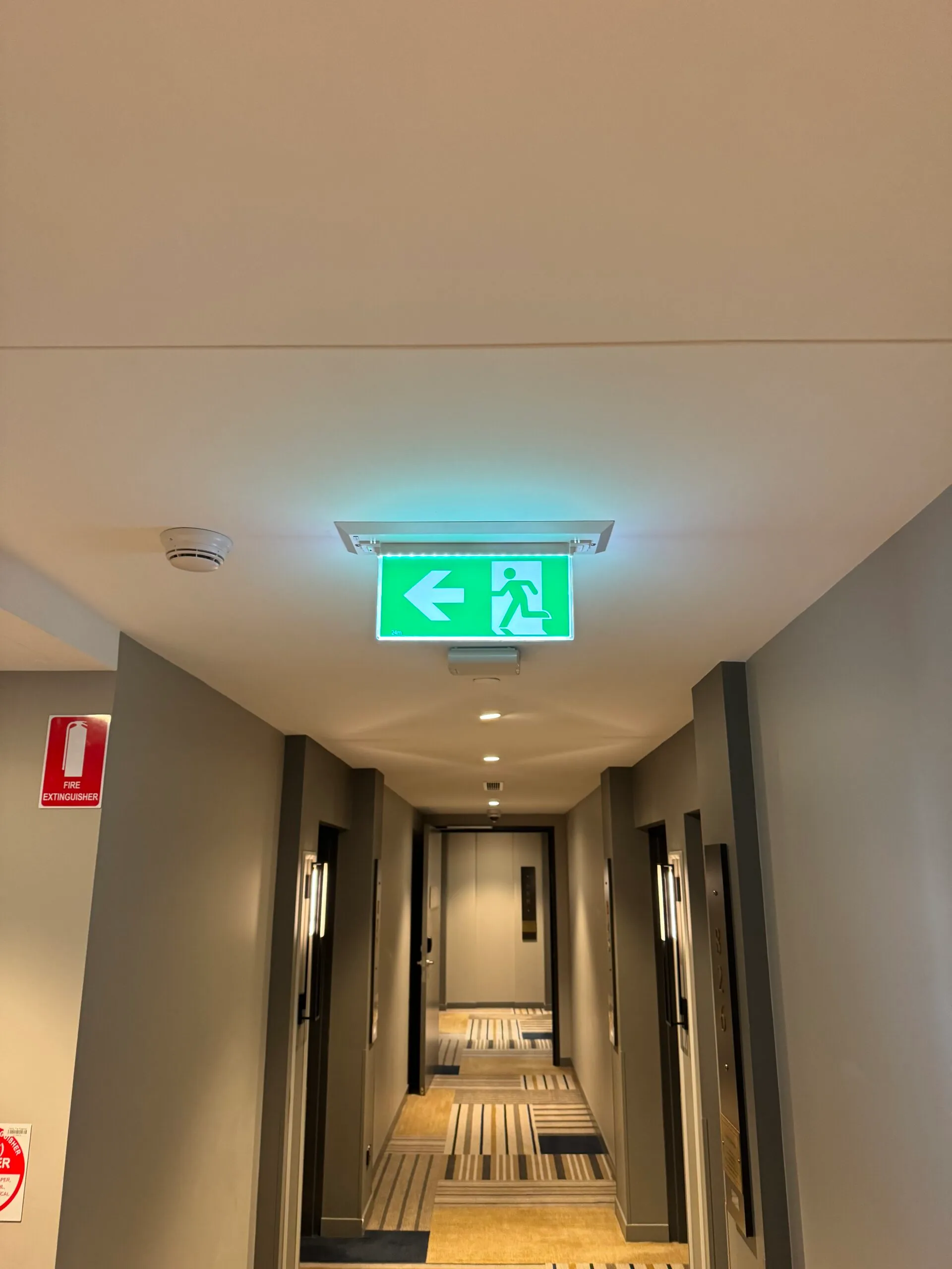 Illuminated emergency exit sign in a hotel hallway installed by Xceed Electrical.