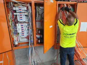 Xceed Electrical technician working on wiring inside an electrical control panel, ensuring safe installation and reliable home security systems.