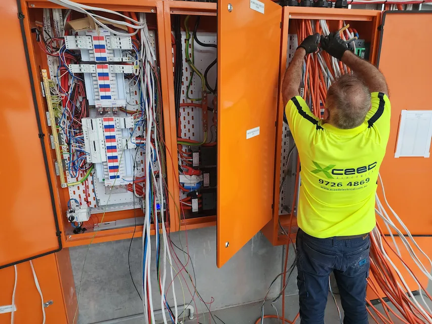 Xceed Electrical technician working on wiring inside an electrical control panel, ensuring safe installation and reliable home security systems.