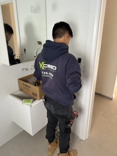 Xceed Electrical technician installing electrical wiring in a residential bathroom.